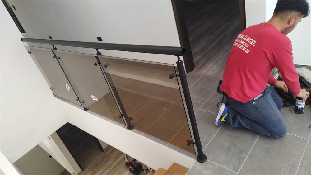 Instalador de Vidrios Lugcel montando una baranda de vidrio en una escalera