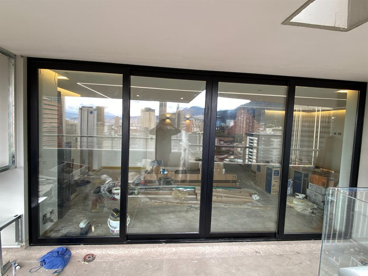 Puerta-ventana de cuatro hojas en un apartamento alto con vista a la ciudad, recién instalada