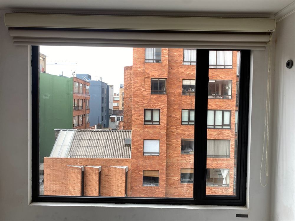Ventana de perfilería negra instalada frente a edificios de ladrillo en Bogotá